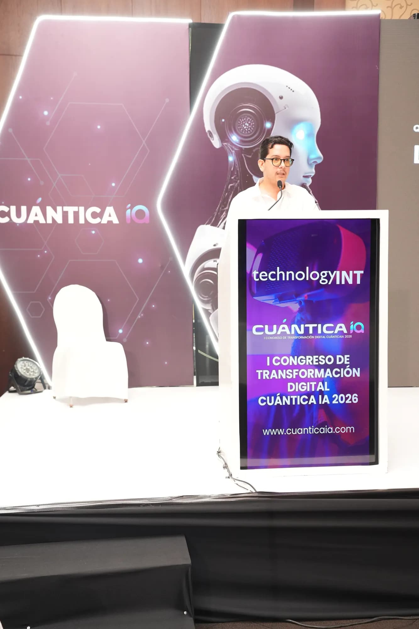 Wide view of the CuánticaIA 2026 stage, with Lucas Pradel at a podium displaying the congress branding and the event website.