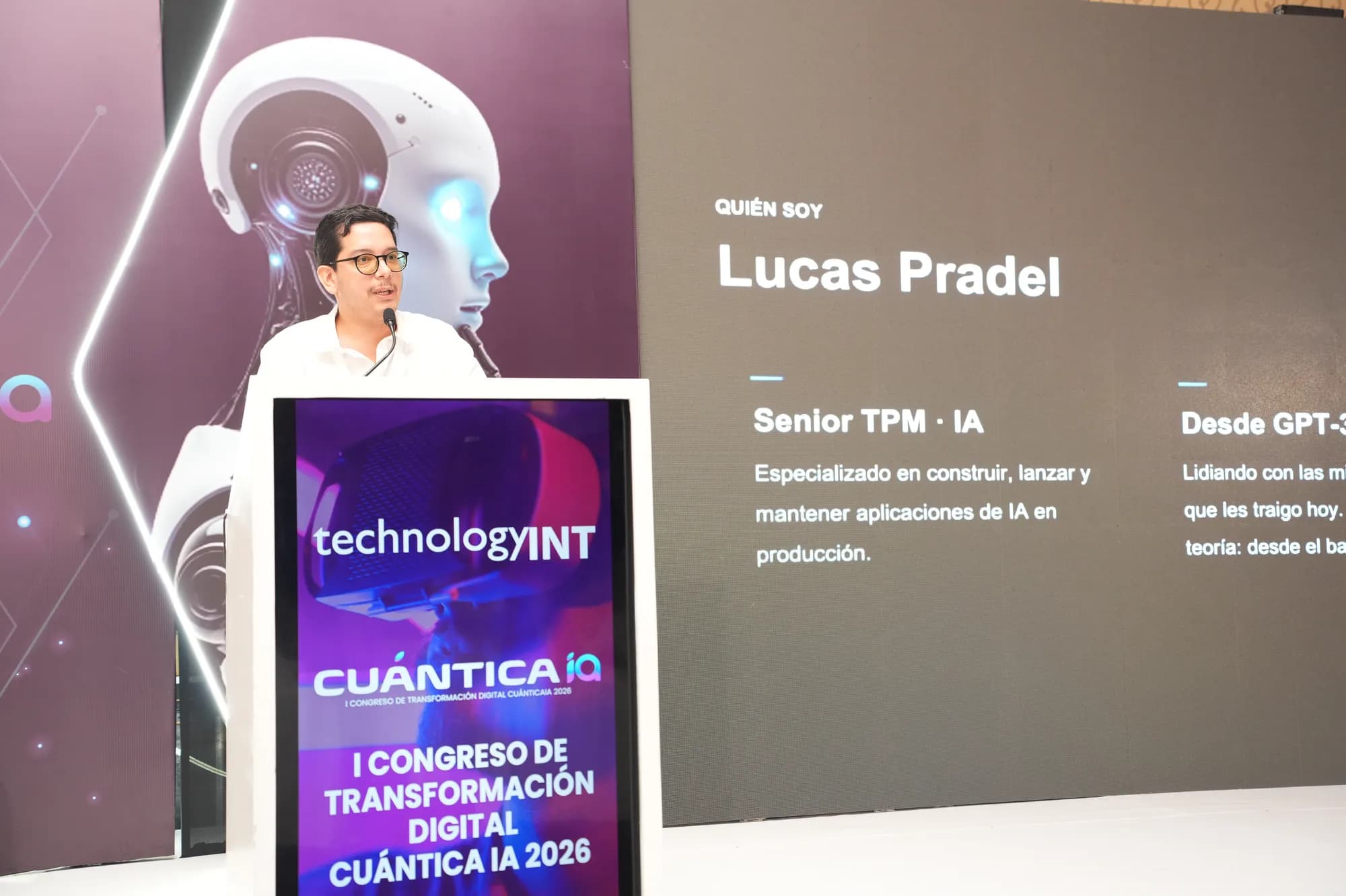 Lucas Pradel speaking at a podium at CuánticaIA 2026, with an introductory slide reading 'Quién soy — Lucas Pradel, Senior TPM · IA' projected on the screen behind him.